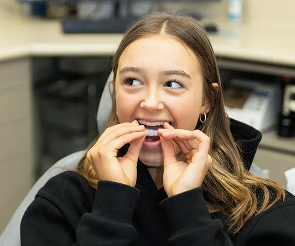 Patient placing a clear Invisalign aligner at The Smile Place Mt Eliza