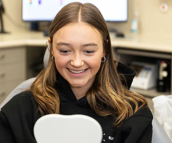 Patient looking at her smile in a mirror at The Smile Place Mt Eliza